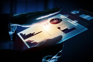 Close up of hands holding tablet showing a virtual dashboard of an ERP system